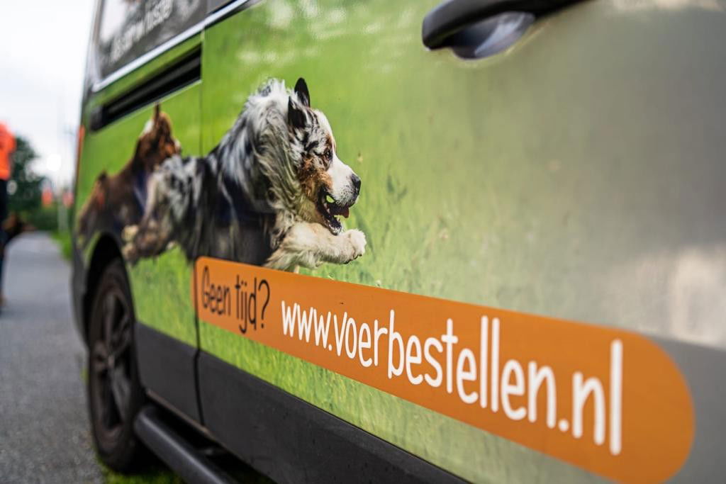 Een busje van de dierenspeciaalzaak met twee rennende honden erop en een link van www.voerbestellen.nl