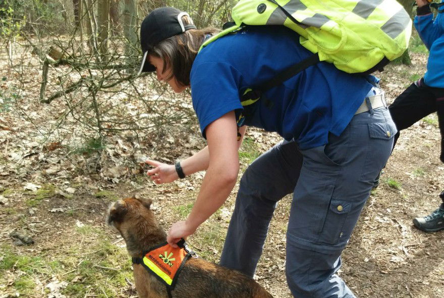 Baasje Esther houdt Lloyd vast terwijl ze naar een stuk bos wijst